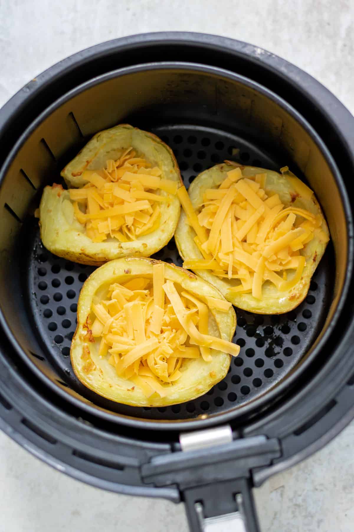 Cheese added to the potato skins in the basket of the air fryer.