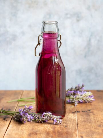 A wooden table with a bottle of lavender simple syrup.
