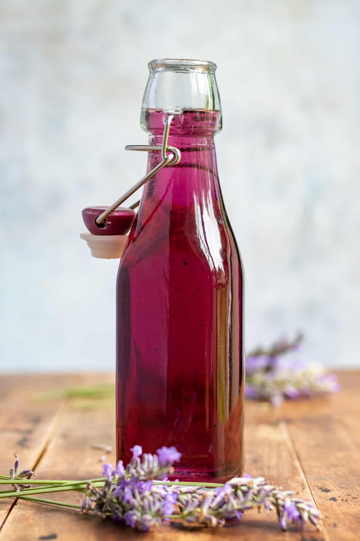 A bottle of homemade lavender syrup next to sprigs of lavender. 