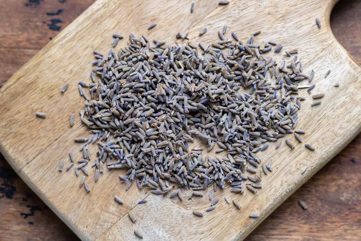 Edible dried lavender buds on a wooden board.