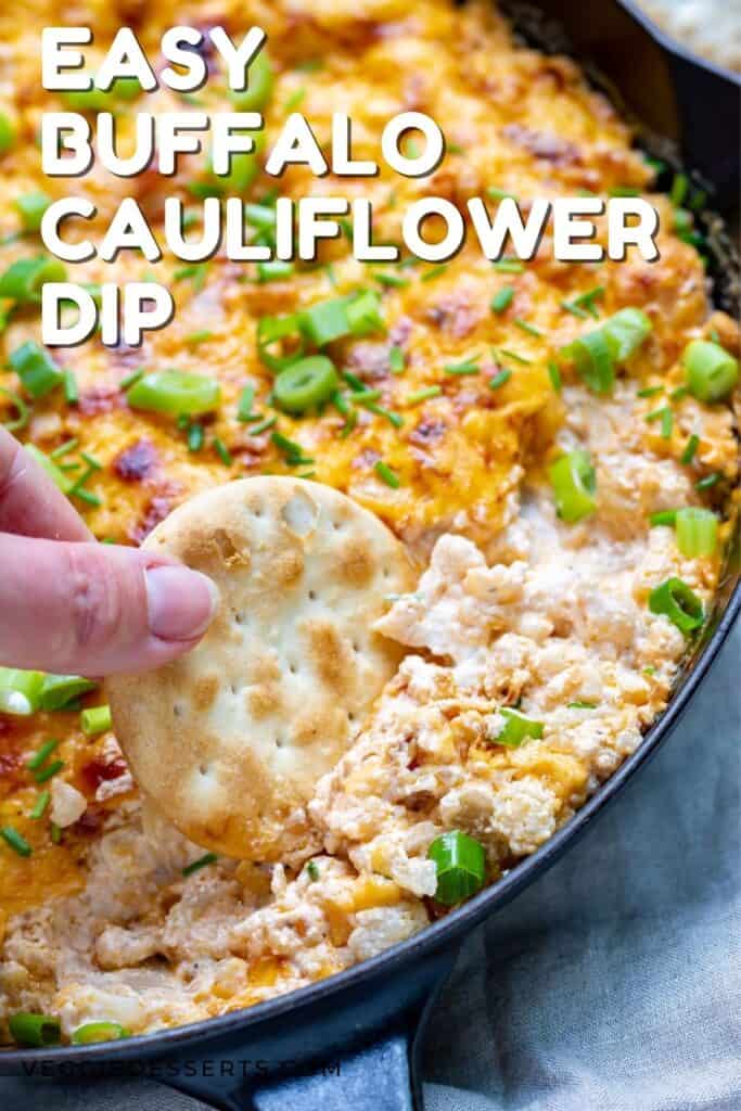 Hand dipping a cracker into dip with text: easy buffalo cauliflower dip.