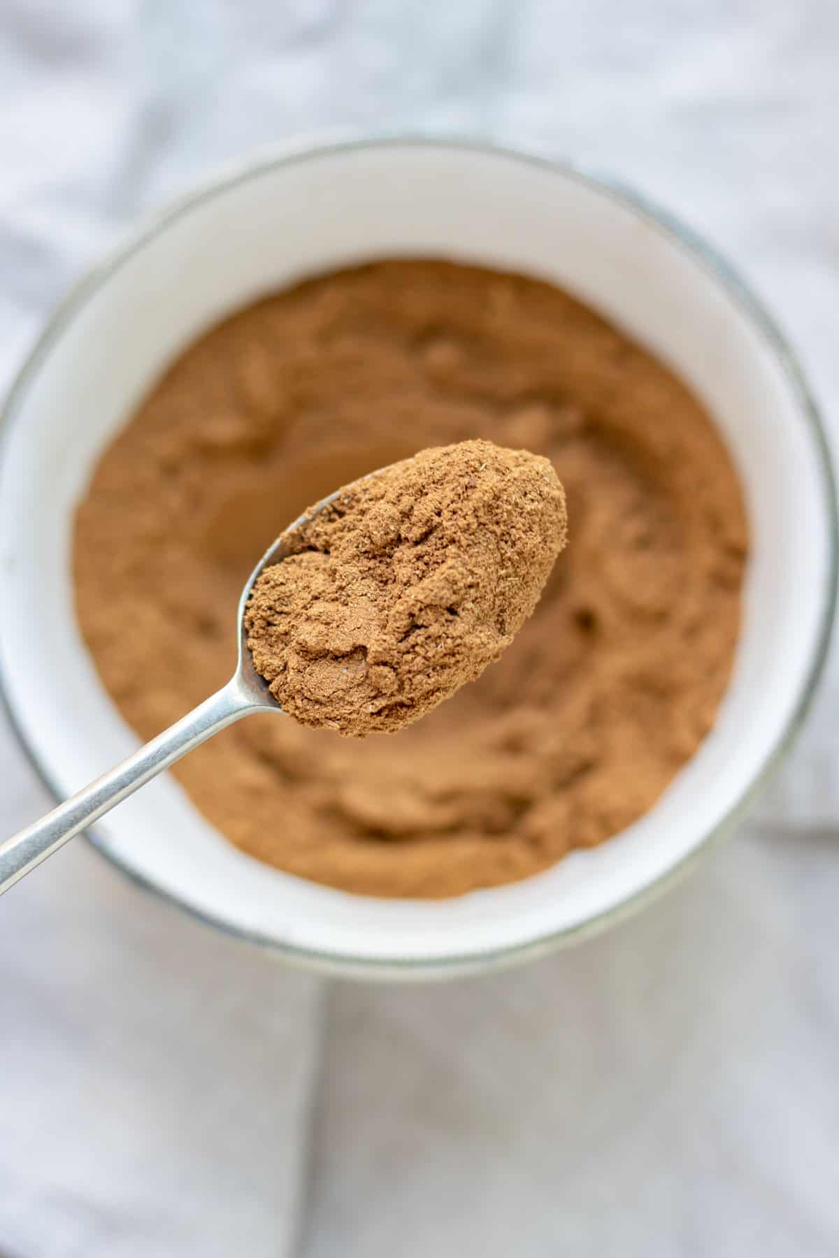 A spoonful coming out of a bowl of chai spice mix.