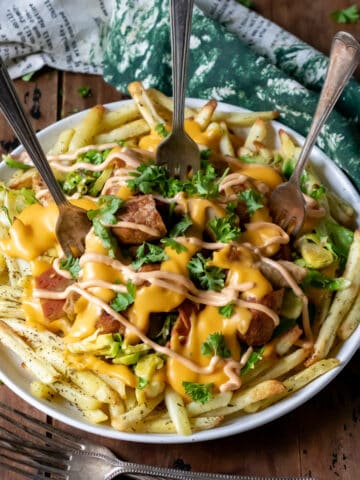 A plate of Christmas loaded fries with three forks in it.