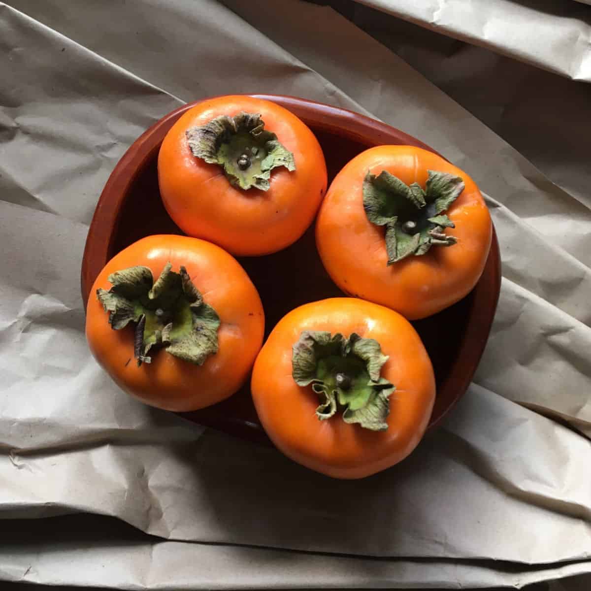 Four persimmons on a plate.