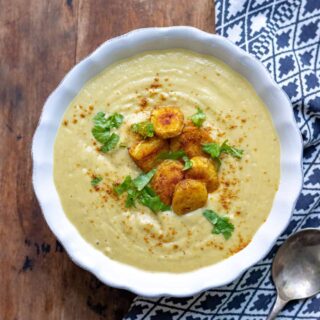Bowl of soup with slices of roasted parsnip on top.