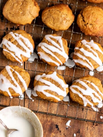 Cookies on a rack, and a bowl of icing.
