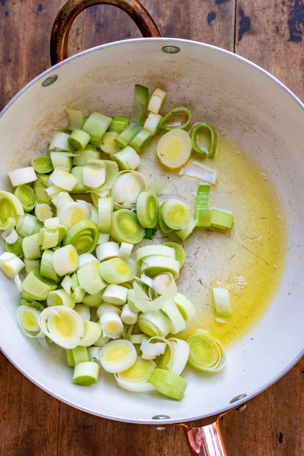 Chopped leeks in a skillet with melted butter.