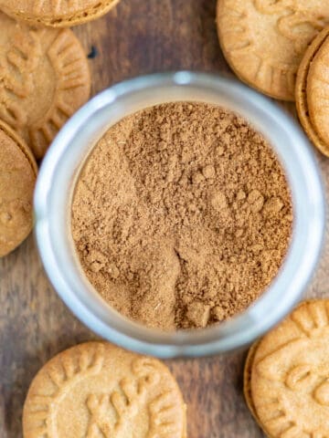 A jar of speculoos spice surrounded by Lotus cookies.