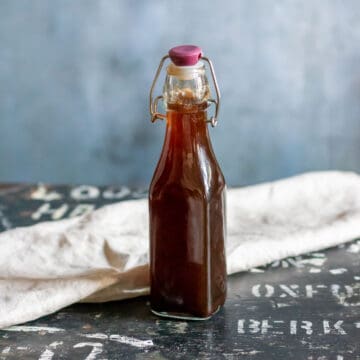Bottle of chai simple syrup on a wooden table.