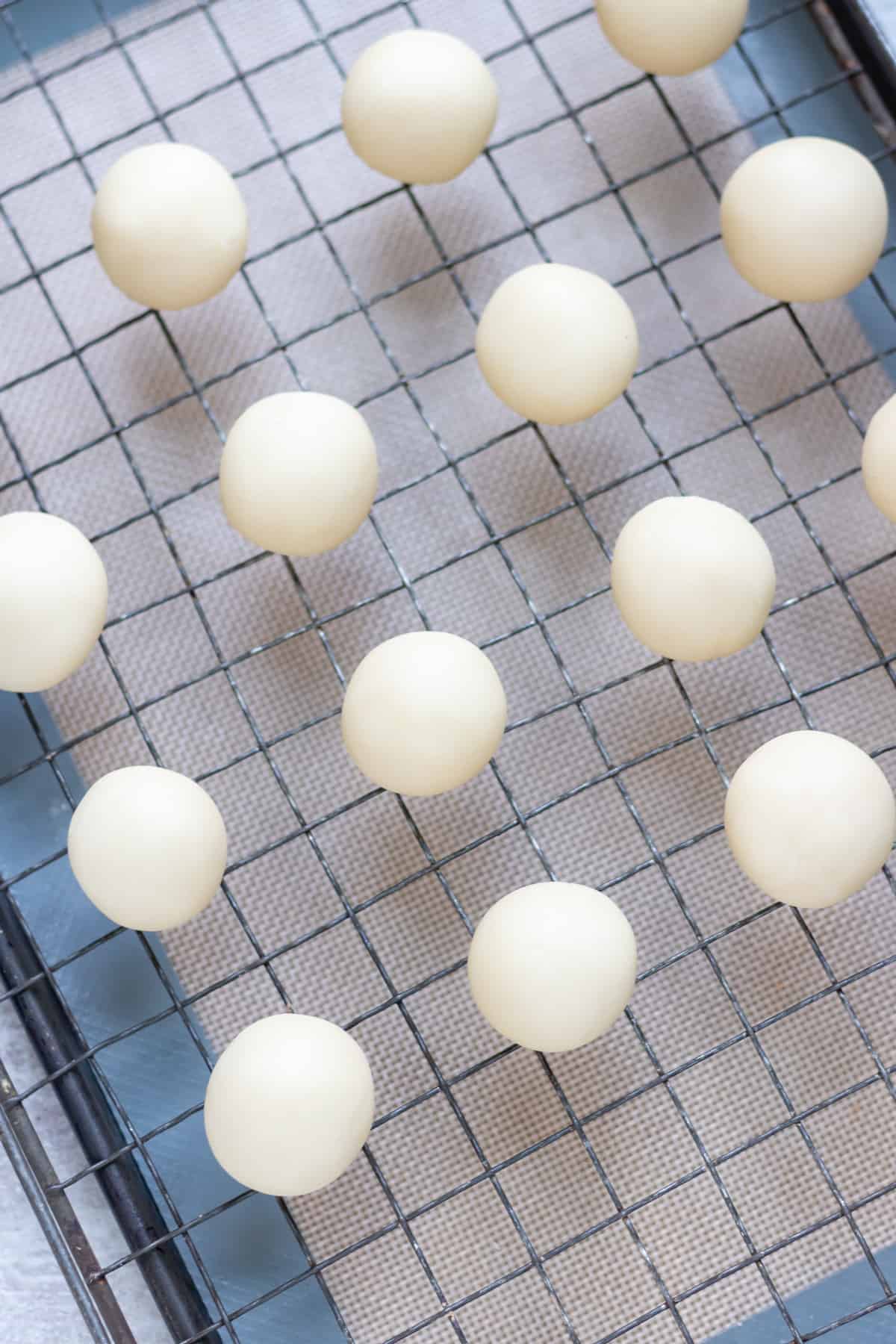 Balls of marzipan on a rack.