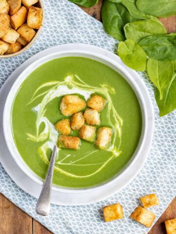 A table with a bowl of soup topped with croutons.