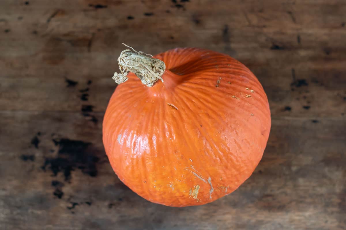 A red kuri squash on a wooden table.