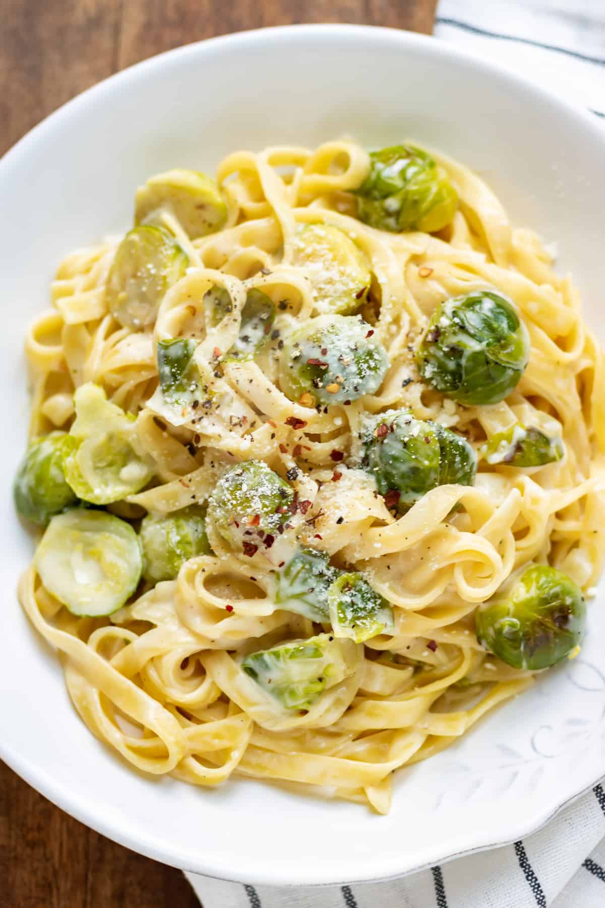 Close up of a plate of pasta with alfredo sauce and sauteed sprouts.