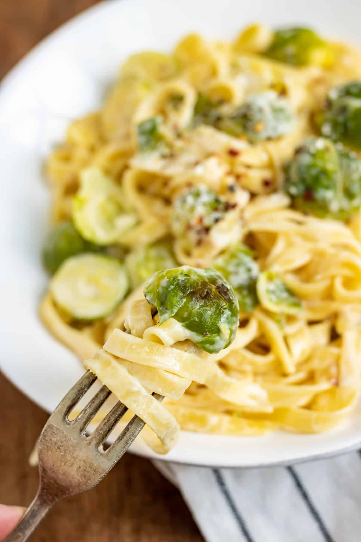 A forkful of brussels sprout pasta being lifted from the plate.