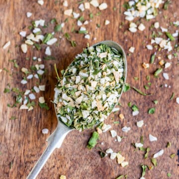 A teaspoon of dill seasoning on a wooden table.
