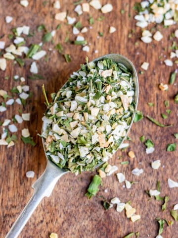 A teaspoon of dill seasoning on a wooden table.