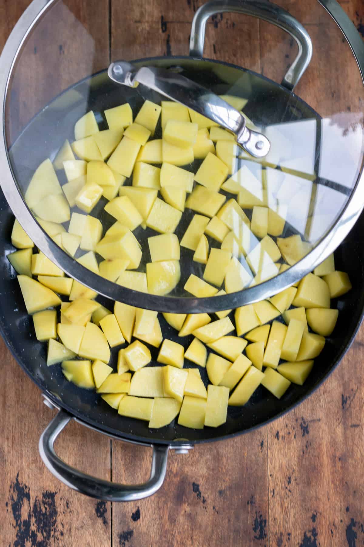 Cubed potatoes in a pan with a lid.