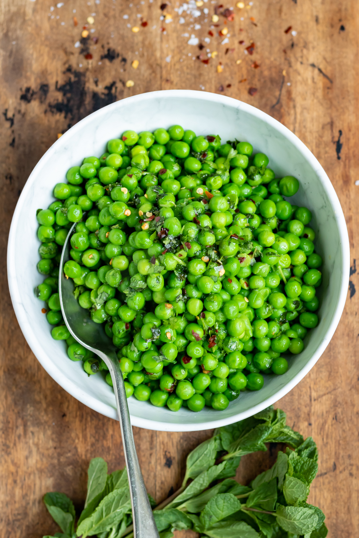 A table with a bowl of cooked peas.