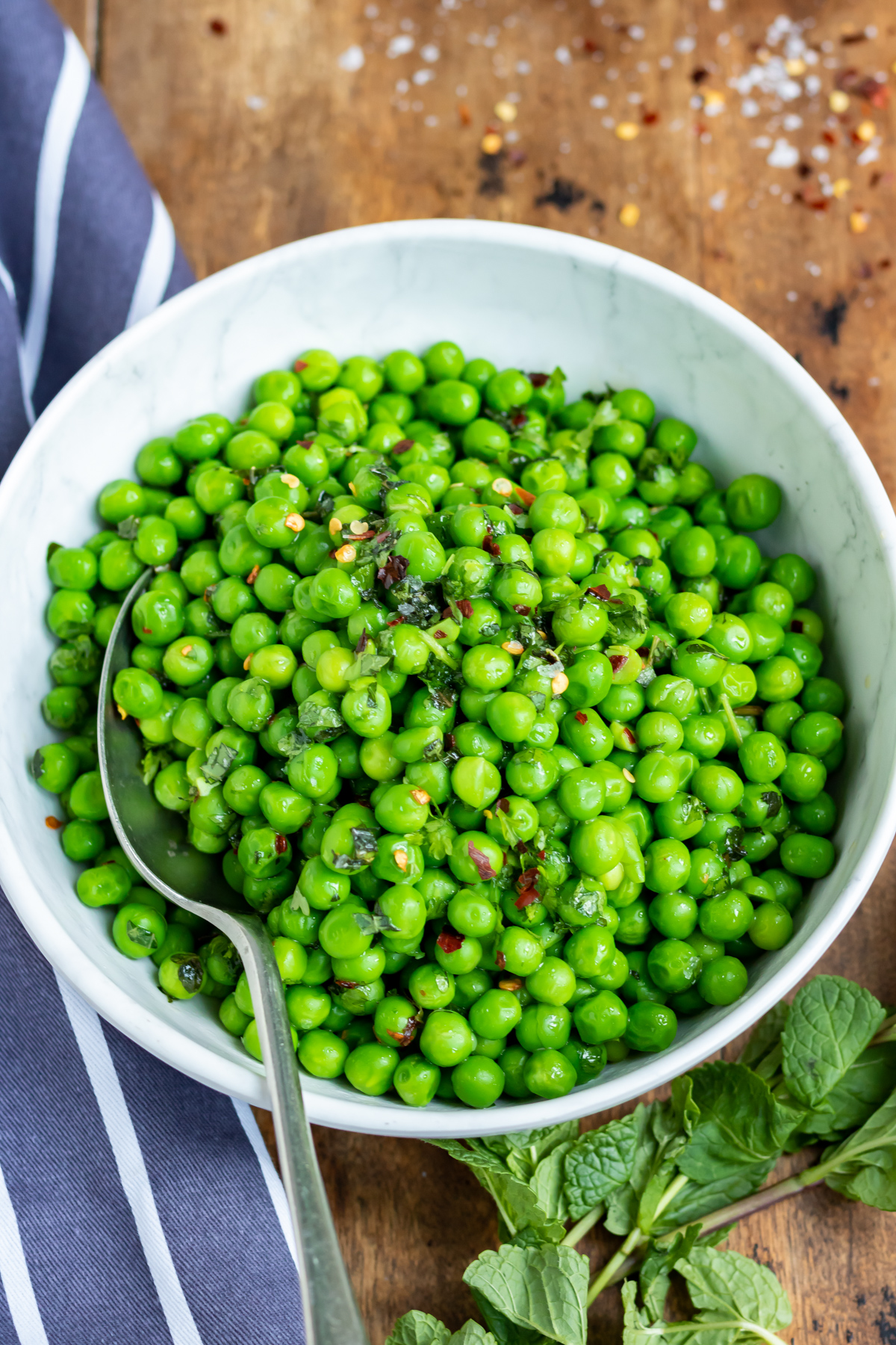 A table with a bowl of cooked peas.