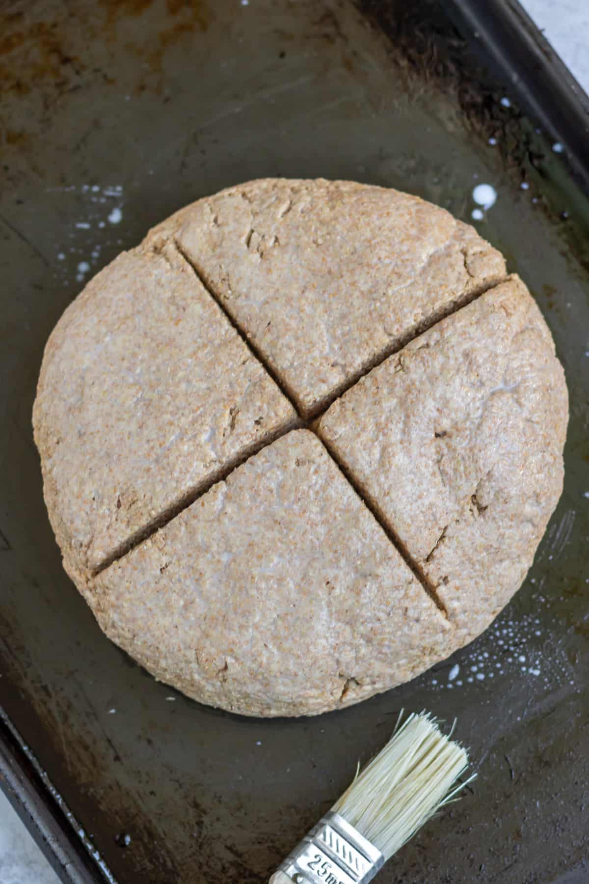Patted into a round on a baking sheet and a cross cut.