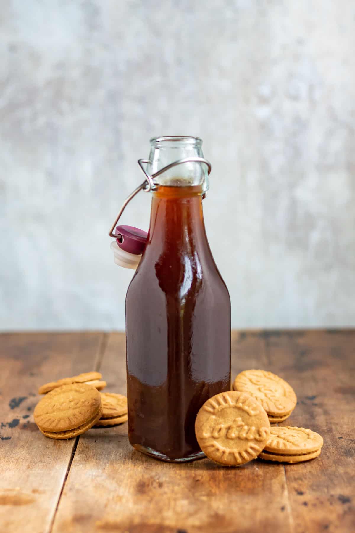 A bottle of syrup next to biscoff lotus cookies.