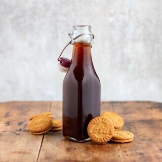A bottle of syrup next to biscoff lotus cookies.