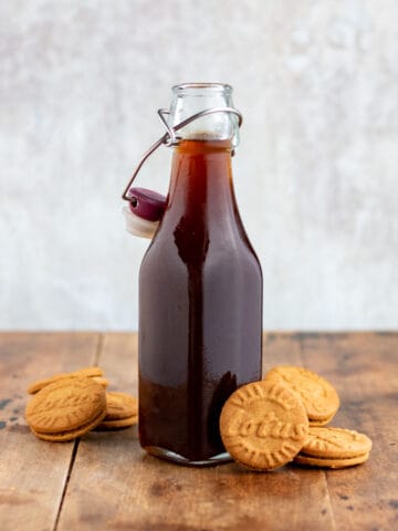 A bottle of syrup next to biscoff lotus cookies.