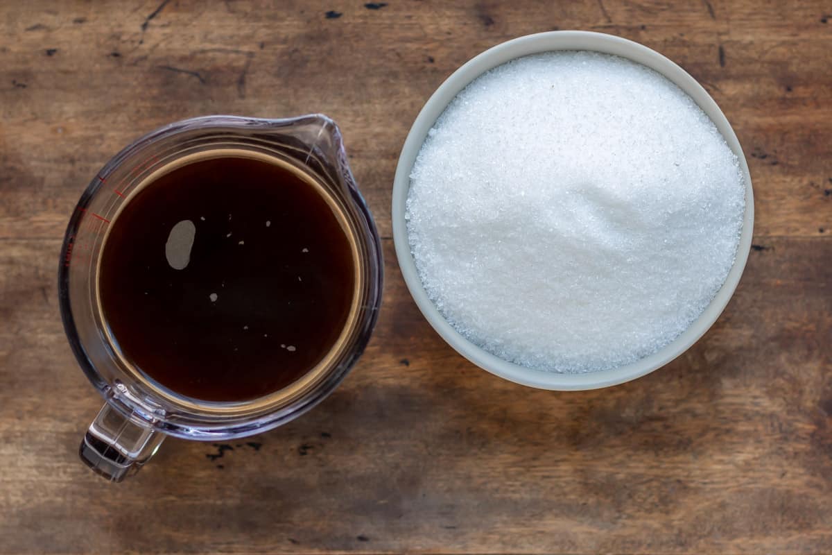 A wooden table with a jug of coffee and bowl of sugar.