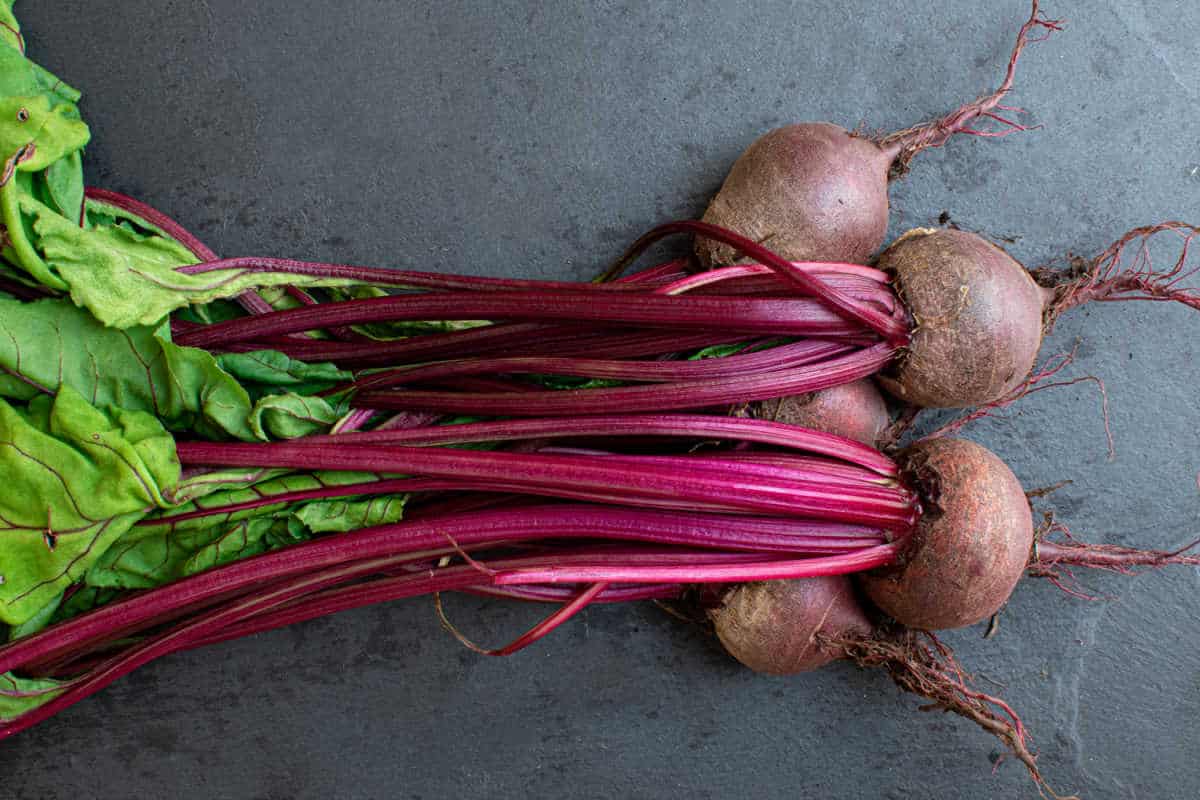 A bunch of beetroot on a black board.