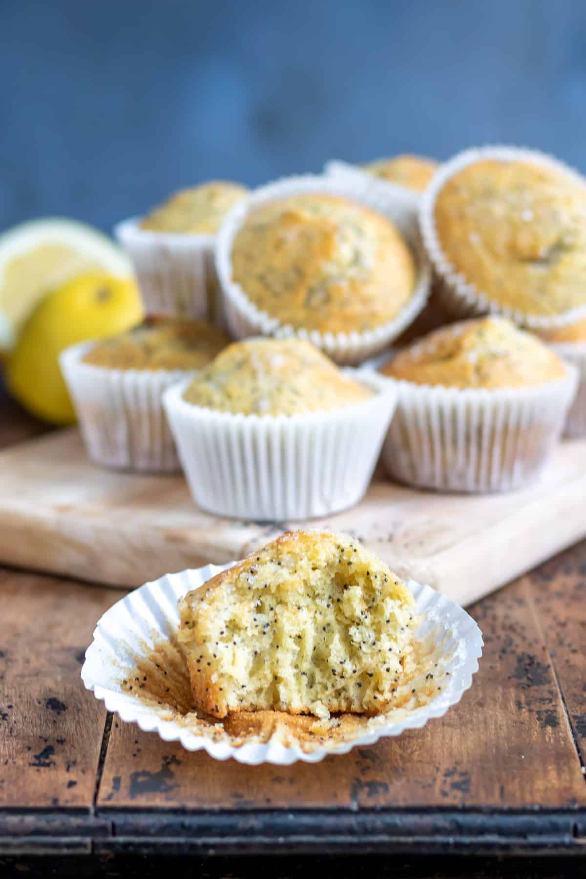 Muffin with a bite out in front of other lemon poppyseed muffins.