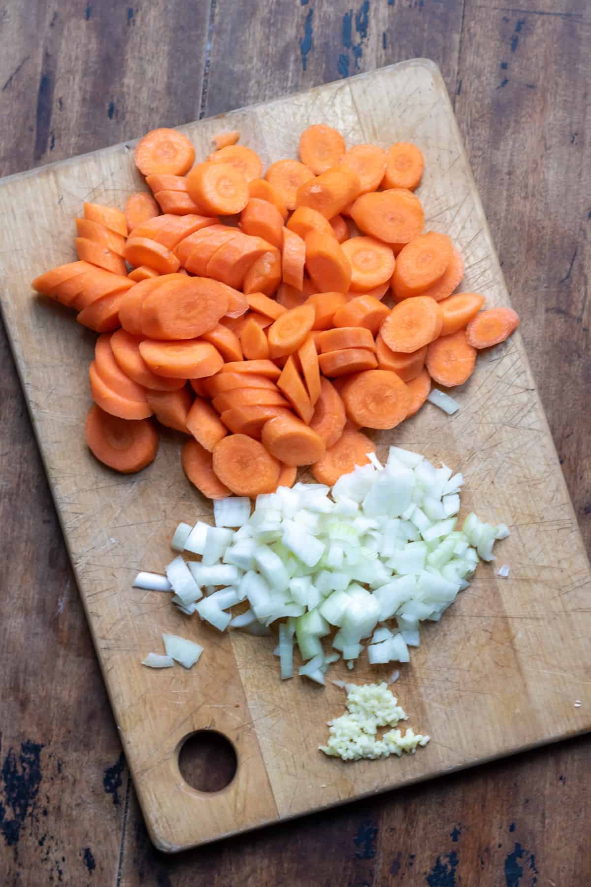 A cutting board with carrots and onions.