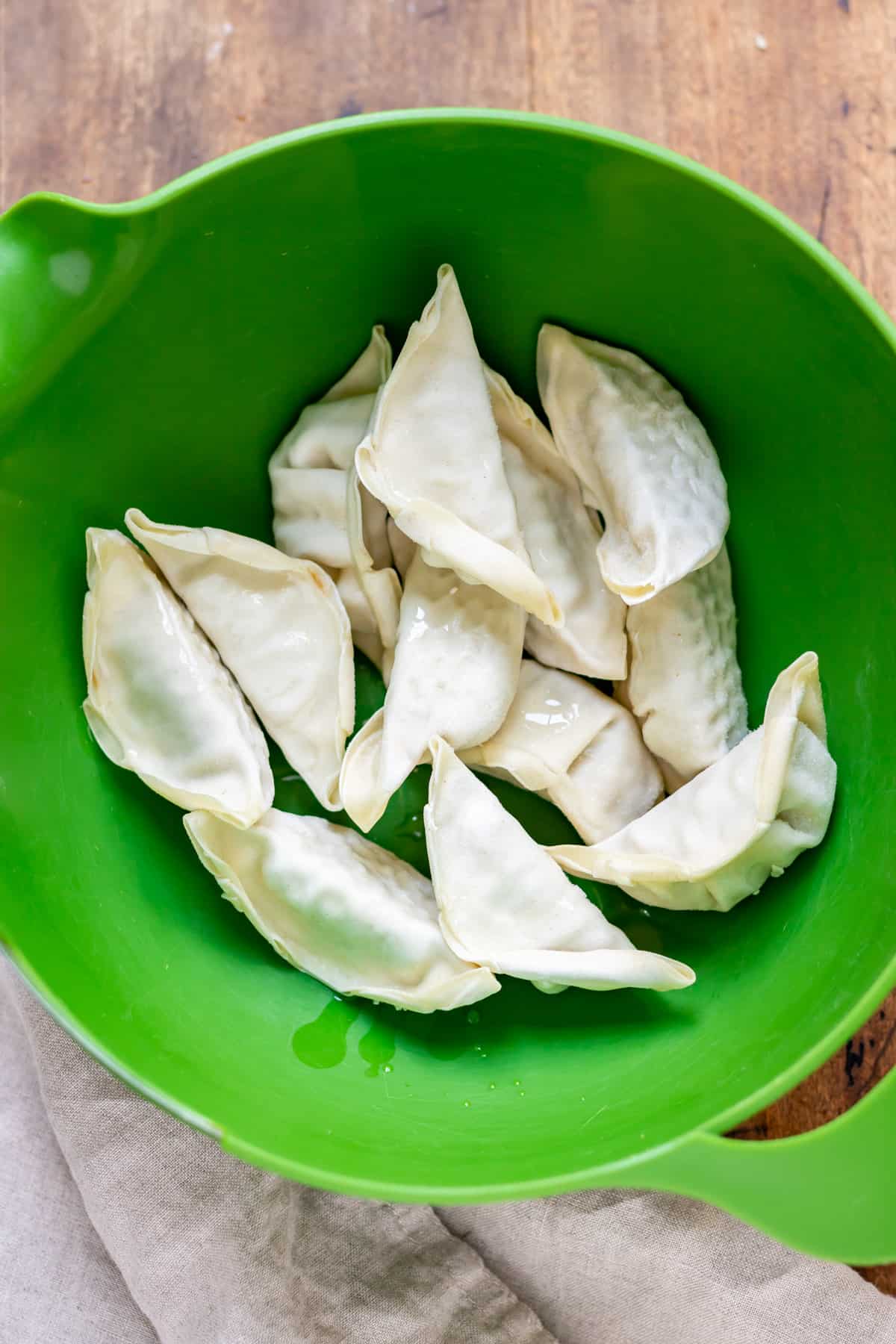 Potstickers in a bowl with a little oil.