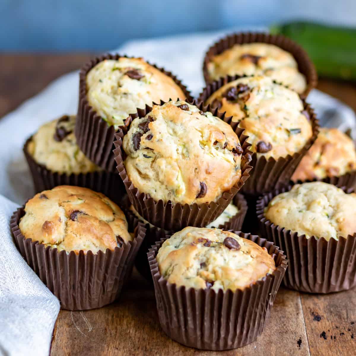 Pile of chocolate chip zucchini muffins on a table.