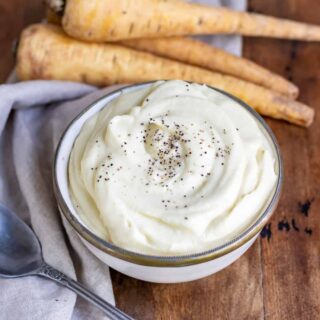 Table with a bowl of parsnip puree next to parsnips.