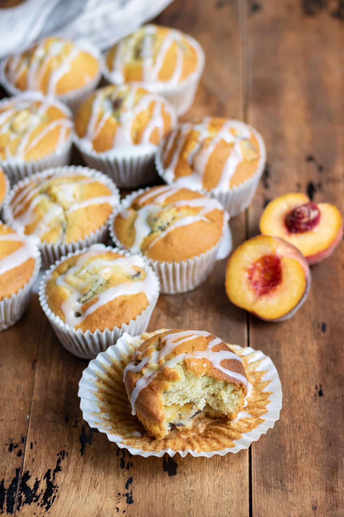 Muffins on a table next to peaches.