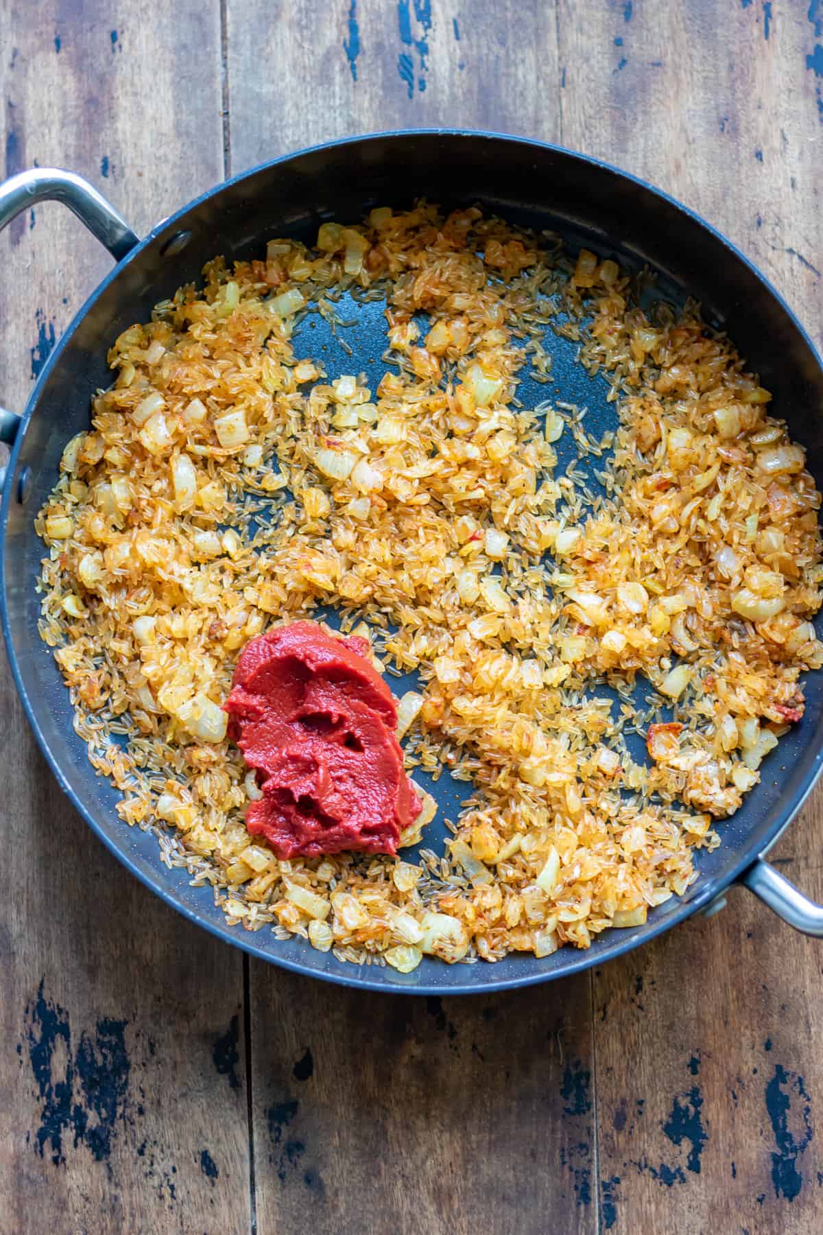 Adding spices and tomato paste to the pan.