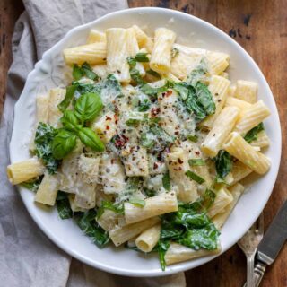 Plate of goat cheese pasta with spinach, on a table.