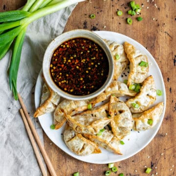 Table with a plate of gyoza and sauce.