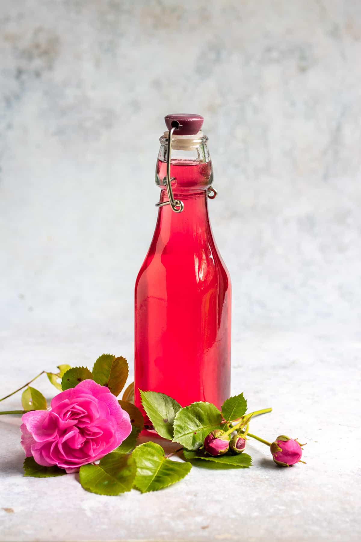 Bottle of syrup next to roses.
