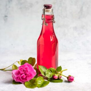 A bottle of syrup and some roses.