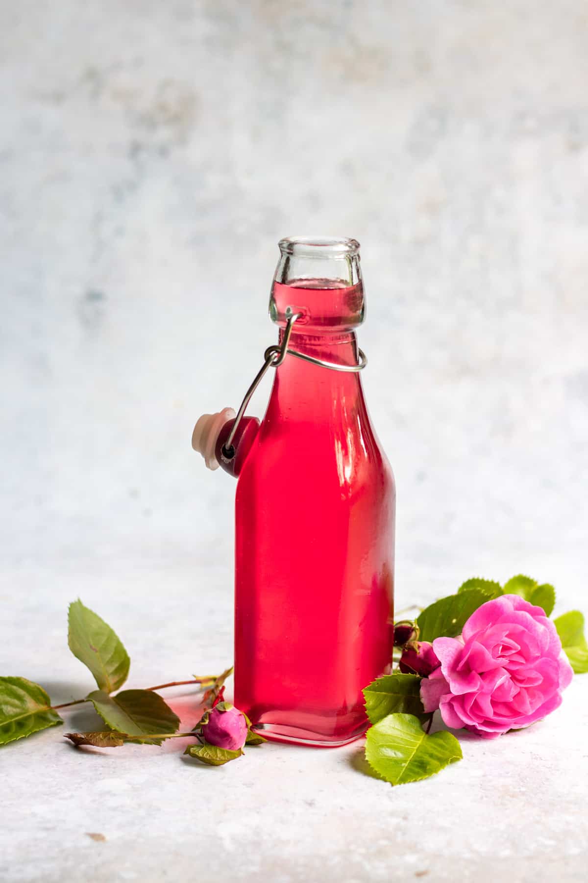 Syrup in a bottle next to some roses.