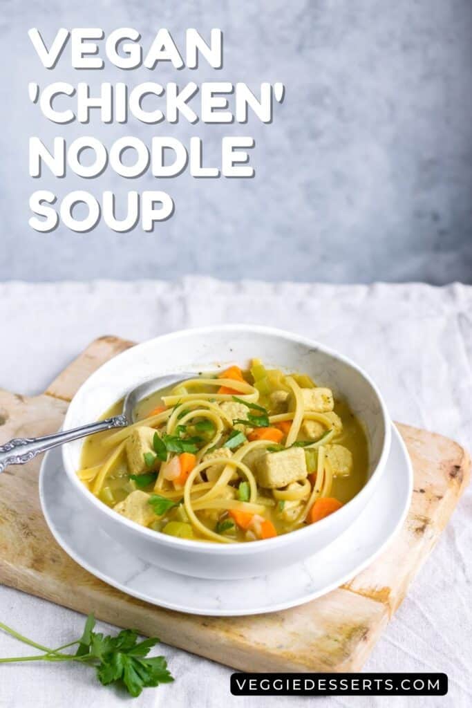 Table with a bowl of soup, plus text: Vegan Chicken Noodle Soup.
