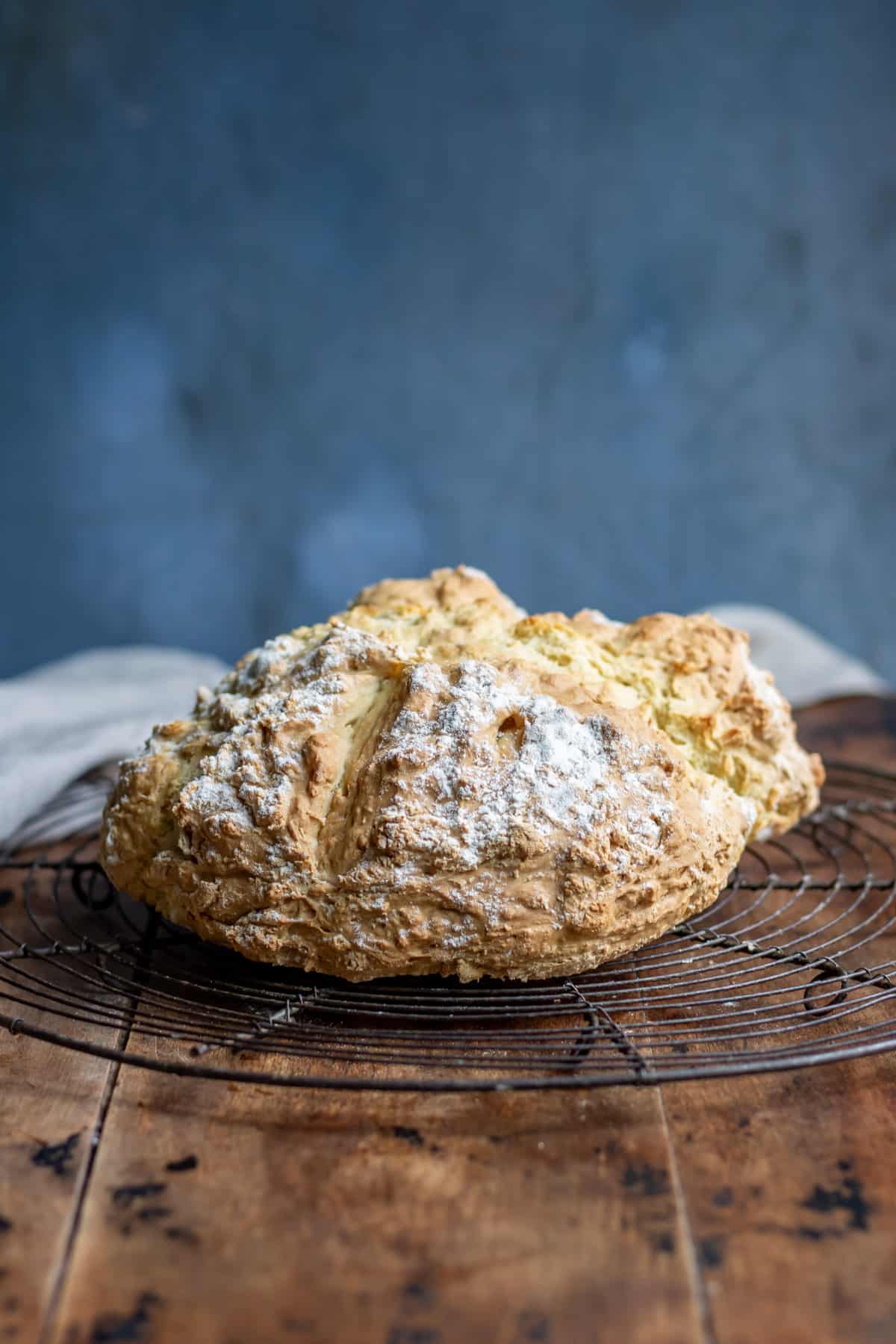 A round loaf of Irish soda bread on a wire rack.