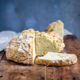Table with a loaf of white soda bread, with a slice next to it.