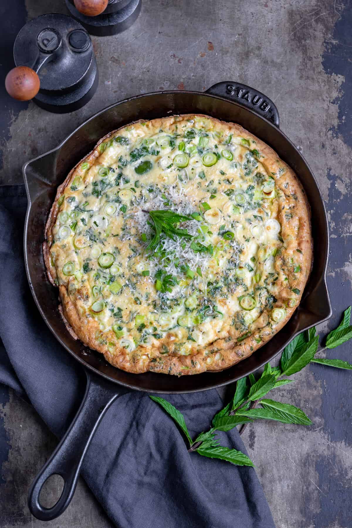 A table with a cast iron skillet of broad bean frittata.