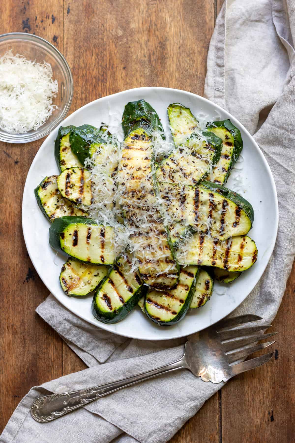 Wooden table with a serving dish of grilled zucchini.