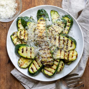 Wooden table with a plate of zucchini.
