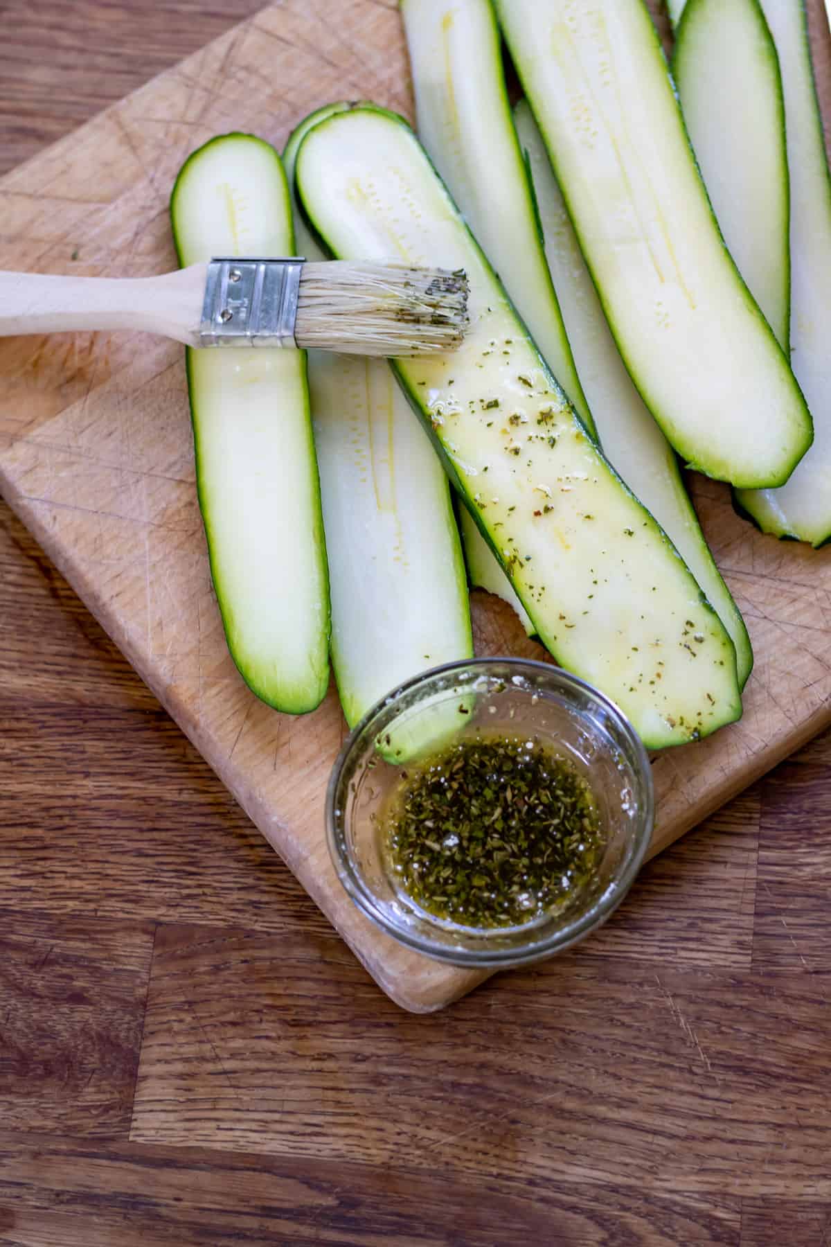 Brushing the zucchini with oil and seasoning.