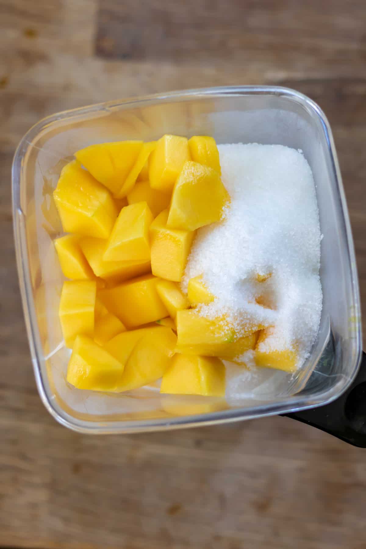 Mango, yogurt, sugar and ice in a blender.