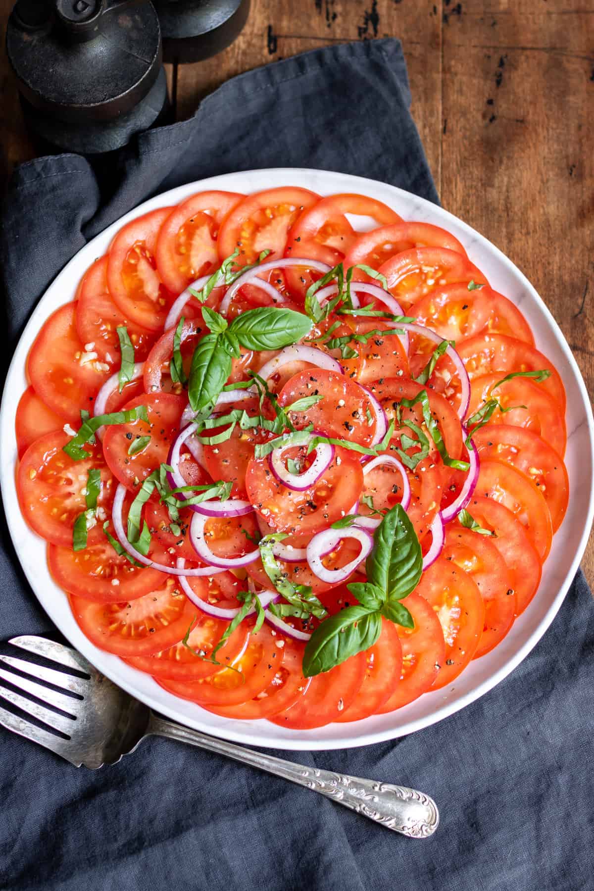 Wooden table with dish of tomato and onion salad.